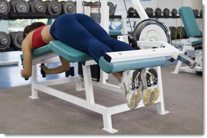 female performing lying leg curls in the gym